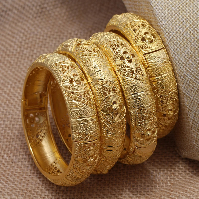 Set of 24k Dubai gold color bangles from LAQTA with intricate design and shiny gold finish, displayed on a neutral background.