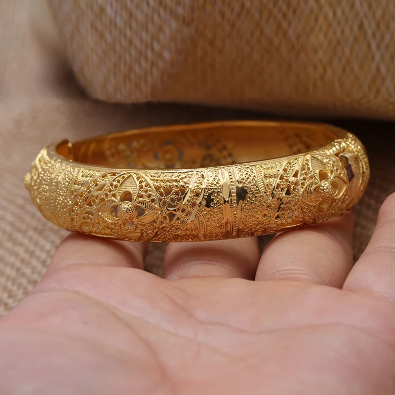 LAQTA 24k Dubai gold color bangles stacked, showcasing shiny gold finish and intricate design on traditional jewelry.
