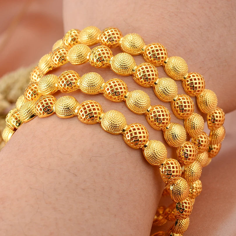 LAQTA 24k Dubai gold color bangles featuring intricate designs and a shiny, polished finish, displayed on a neutral background.