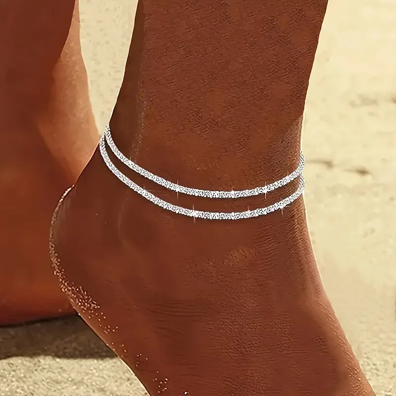 Silver metal pendant anklet by LAQTA featuring intricate designs and delicate chain links for stylish ankle jewelry.