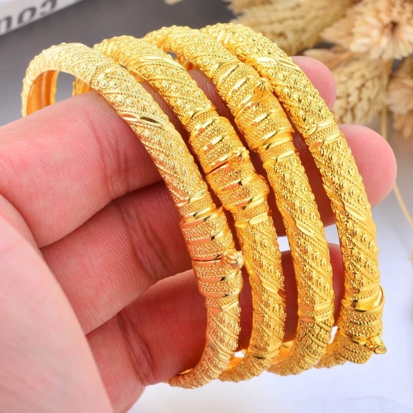 Elegant 24k Dubai gold color bangles by LAQTA, showcasing shiny gold-toned jewelry with intricate designs and smooth finish.
