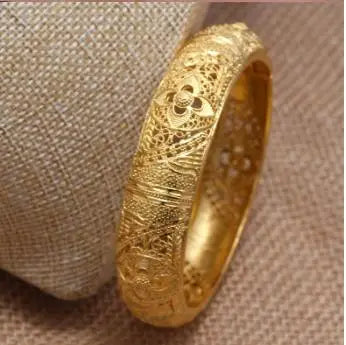 Elegant 24k Dubai gold color bangles by LAQTA, showcasing shiny, detailed gold jewelry on a neutral background.