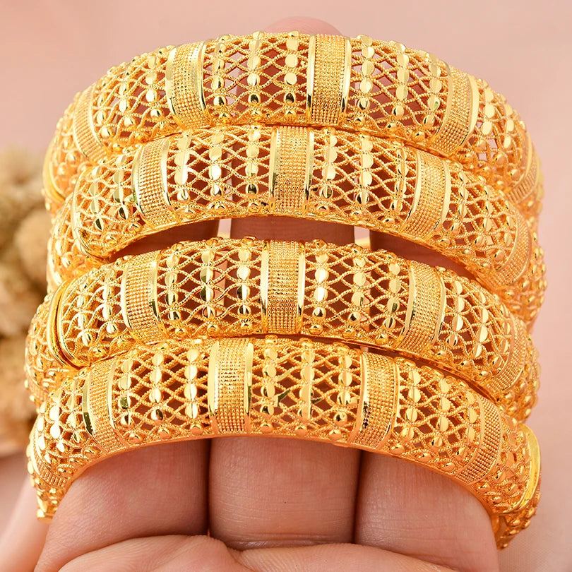 Luxurious 24k Dubai gold color bangles by LAQTA, featuring intricate designs and a shiny gold finish on a white background.