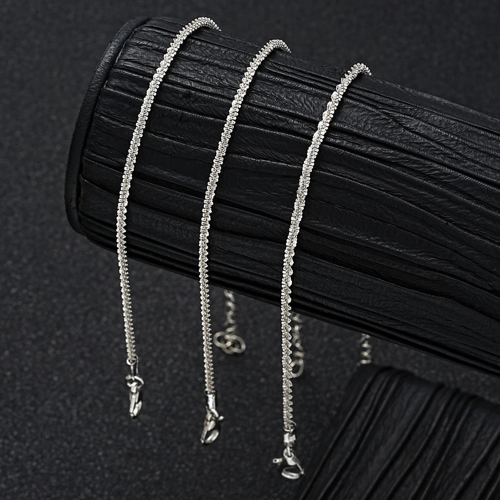 Silver metal pendant anklet by LAQTA featuring intricate design and adjustable chain on a neutral background.