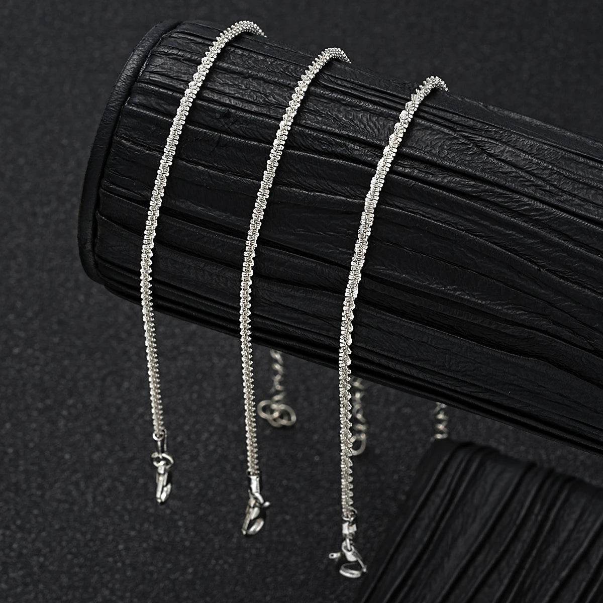 Silver metal pendant anklet by LAQTA featuring intricate design and adjustable chain on a neutral background.