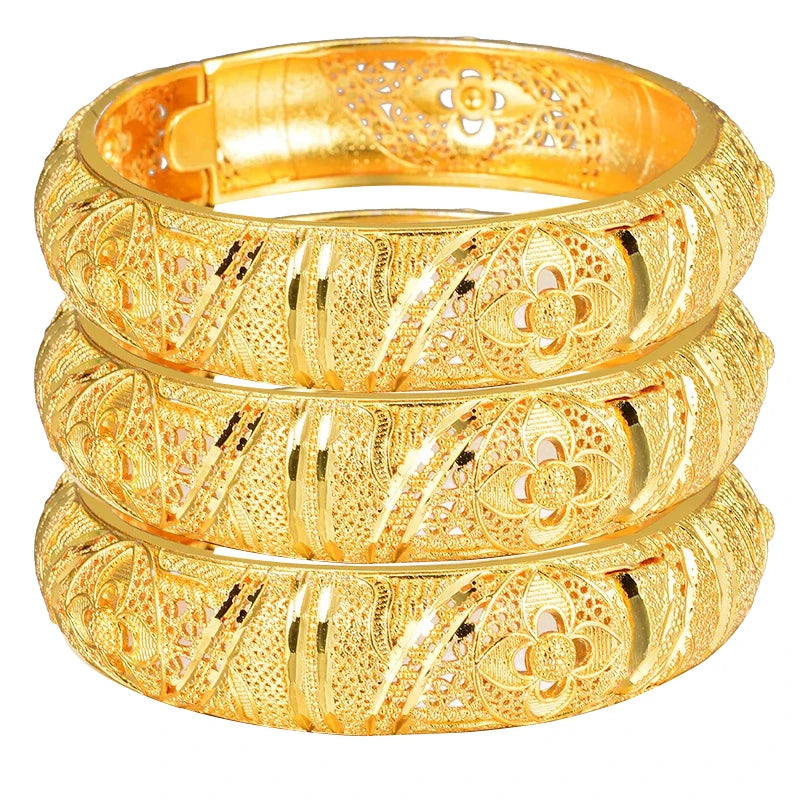 Set of 24k Dubai gold color bangles from LAQTA featuring shiny, intricate gold-tone designs on smooth metallic surfaces.