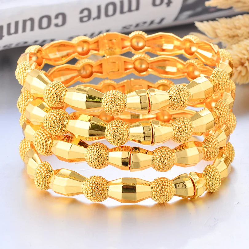 Gold color bangles by LAQTA, featuring intricate Dubai 24k gold finish, displayed in a close-up shot.